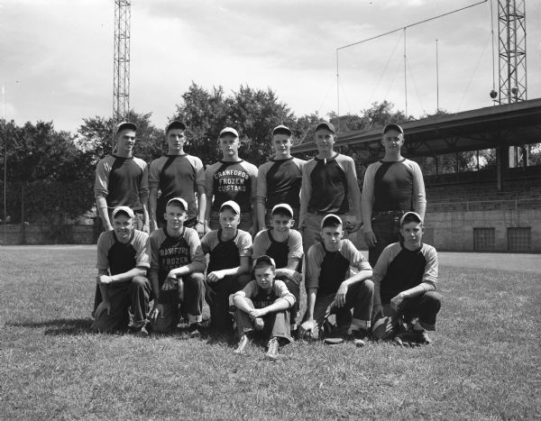 Outdoor group portrait of the Crawford Custard's baseball team, winners of the Senior League of the Boys' Baseball Program by defeating the Durfree Brothers Roofing team. Seated in front row left to right: Danny Crawford, Leroy Silamps, Otto Puls, Gordon Hanson, Dick Ripley, and Billy Day. Standing left to right: John Oasen, Ray Pickarts, Wendell "Windy" Gulseth, Bob Brown, Trig Oliversen, and Frank Hanson. Seated in front is the team mascot, Jimmy Fillner.