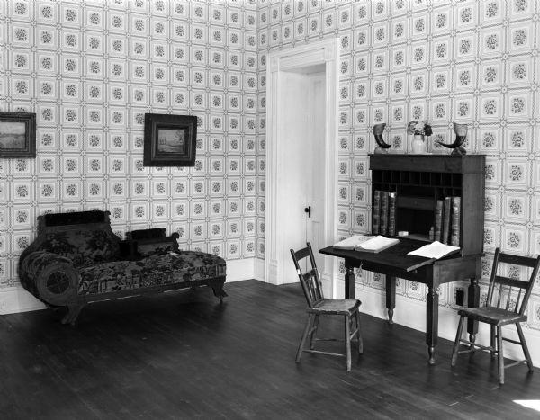 Reception room at the Governor Nelson Dewey house, on his estate called Stonefield. The governor's glasses mark a place in the book on the title desk. On the couch are a silk hat and cane worn at the 1880 Democratic convention in St. Louis.
