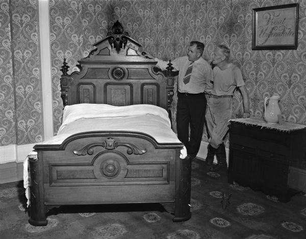 Master bedroom at the Governor Nelson Dewey house on his estate called Stonefield. On the right side are Cassville President R.J. Eckstein, and George W. Foehringer, caretaker of Nelson Dewey State Park. The two men helped trace the bed to Iowa and brought it back to Stonefield in 1949.