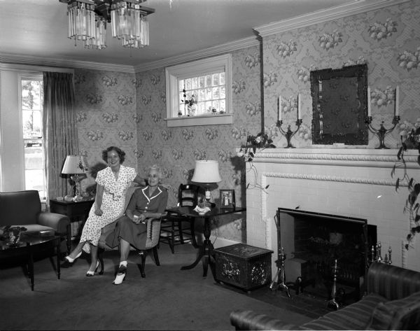 Mrs. W.T. Cartwright, right, and her daughter Jane Cartwright, sitting in the living room of the Howe/Baxter House, owned by Mr. and Mrs. W.C. Cartwright of Lancaster.  One wing was built during Civil War days for the Howe family. The rest was designed in 1914 by the Madison firm of Beatty and Strang for the Baxter family.