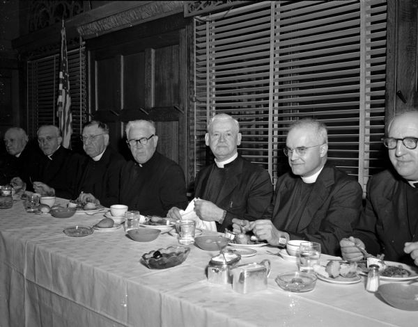 Six Catholic priests at the speakers table with Bishop O'Connor during a welcome home dinner at the Park Hotel after the bishop returned home from a trip to Rome. From left are: an unidentified priest, Rev. Otto Behnke, of the Pallottine Order; the Rt. Rev. Msgr. William H. Eggers, St. Bernard's; Bishop O'Connor; the Rt. Rev. Msgr. William H. Mahoney, St. Rapheal's cathedral; the Rev. Michael J. Jacobs, St. John the Baptist, Jefferson; and the Rev. J.F. Bieneski, Berlin.