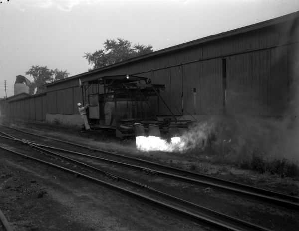 A weedburner of the Illinois Central Railway in action burns ragweed along railroad tracks. The weedburner is a self-propelled unit equipped with an oil-burner and blower that burns weeds on four sides of the tracks.
