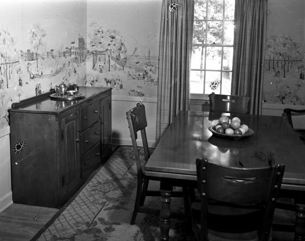 Dining room of the residence of Mr. and Mrs. C.T. (Helen) Rath, 2826 Mason Street. The room is influenced by Early American style with maple furniture enhanced by the chartruese-dominated color scheme, along with accent colors of rose, yellow, beige, and blue.