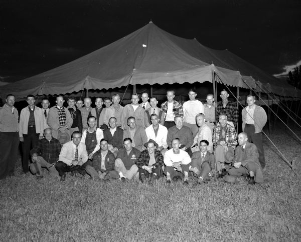 Group portrait of members of the West Side Business Men's association preparing to raise a "big top" tent for the association's annual fund-raising auction.