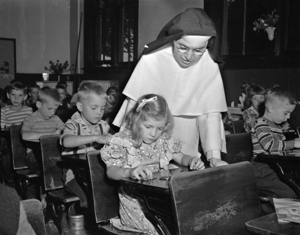 Sister Mary Eulogia, O. P., St. Bernard's School, is shown with first graders Jean Ann Kiefer and her brother, Jerry Kiefer, in a classroom. The children of Mr. and Mrs. Robert A. Kiefer, Route l, Madison, are among 55 first-graders who started school at St. Bernard's, 2430 Atwood Avenue.