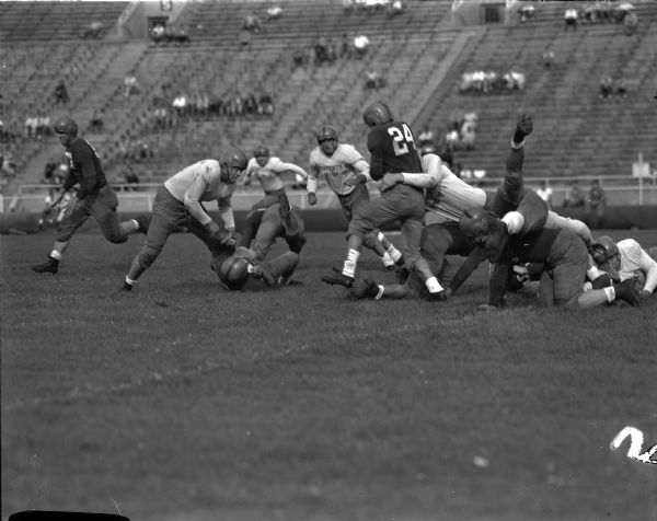 Gwynn Christensen, Lake Mills, is being tackled by Pat O'Donahue, Eau Claire, as Charlie Meyer, Janesville, and Billy Lane, Edgerton close in during a University of Wisconsin football scrimmage at Camp Randall Stadium.