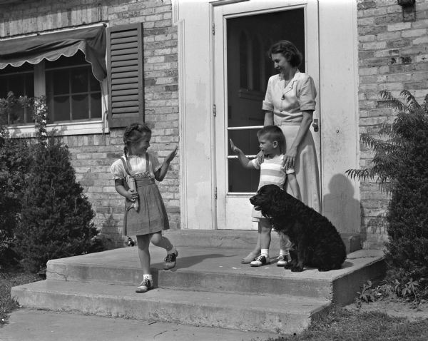 Five-year-old Jenna Icke waves to her mother Mrs. George W. Icke, and to her brother, Phil, and dog, Tippy, as she heads off to school for the first day of class.