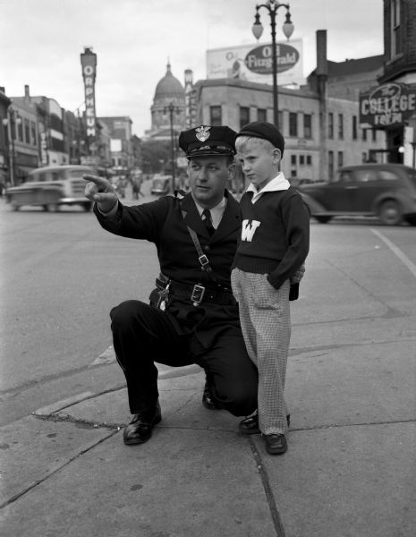 Traffic officer Hector Naze, who directs morning traffic at the corner of Johnson and State Streets, is shown explaining the crossing rules to seven-year old Freddy Milverstedt, son of Mrs. and Mrs. Fred (Margaret) Milverstedt, 131 Langdon Street. Freddy is in the second grade at St. Raphael's parochial school.