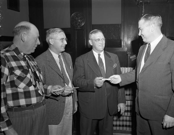 Charles F. Esser (right), first aid chairman of the Dane County Red Cross, presenting certificates of first aid for fifty-two members of the county traffic, sheriff, and highway departments. Accepting the certificates are, from left: Captain O.F. Larson of the Dane county highway police, Ray H. Swann, county highway commissioner, and Sheriff Herman P. Kerl.
