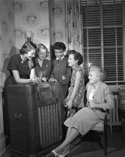 Mrs. Florence Marquart, recently from Milwaukee, the new director of resident girls at the YWCA, shown at the left, enjoying a radio program with some of the young women who make their home at the YWCA.
From left to right the girls are: Sylvia Song, Shanghai, who is studying for a PhD degree in chemistry; Lydia Monroe, Harvey, Illinois, a nurse anesthetist at St. Mary's Hospital; Jeanne Clancy, East Troy, a legal secretary; and Irene Van Horn, of Ft. Atkinson, a student at the Wisconsin School of Music. 
The Young Women's Christian Association is located at 124 North Carroll Street.