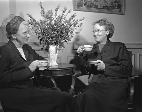 Jessie McCanse, President of the Board, and Edna Westerstrom, new Executive Director, sit together to drink a cup of coffee. They were present at the "open house" for the YWCA open home week. The YWCA is located at 124 North Carroll Street.
