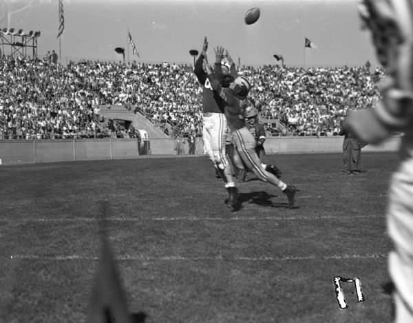 University of Wisconsin vs. Marquette football game. Harold Haberman, Wisconsin End, is shown receiving a pass from Marquette Halfback, Vic Wojoik.