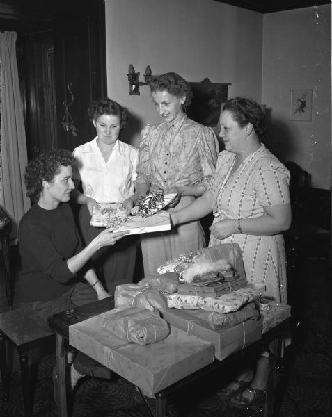 Three women, employees of Oscar Mayer Company, present gifts to co-worker Irene Loveland who lost her home and personal possessions in a fire. Left to right: Irene Loveland, North Freedom; Miss Schumacher, Polly La Barro, and Hilda Johnson.