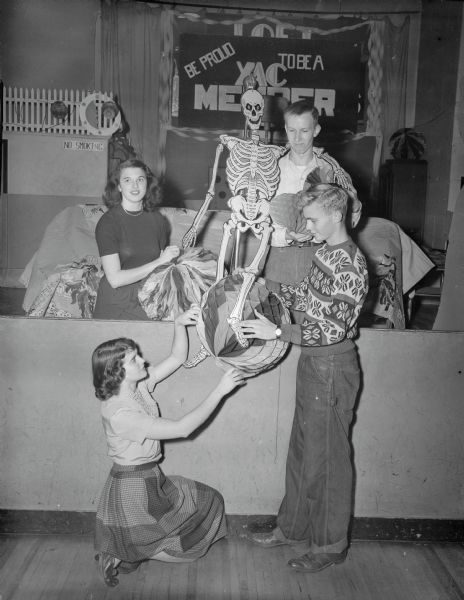 Madison high school students preparing for a Halloween party and dance at the LOFT. Kneeling is Phyllis Robinson, Central High School, director of decorations for the party. At lower right is Fred Mansanger, East High School; at upper right is Mary Ellis, Central High School, and at upper right is Carvet Miller, West High School.