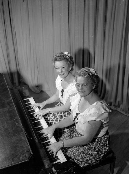 Mrs. Lloyd W. (Mildred) Coleman, at left, and Mrs. J. Gibson (Marion) Winans, at right, playing a piano duet as part of the program for the Shorewood Hills League's annual cabaret party.