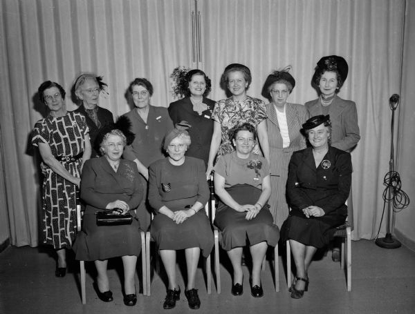 Group portrait of the Ways and Means Committee of the Madison Business and Professional Women's Club. Seated, left to right: Jessie Harloff; Edna Lundy; Dr. Christine Thelen, club president; and Alice Hemingway, committee chairman. Standing are: Ann Golden, Mary O'Connell, Lorena Rawles, Laura Weinand, Edith Allmquist, Irene Crowley and Lois Allen Hart. They are meeting to plan a card party to raise scholarship money.
