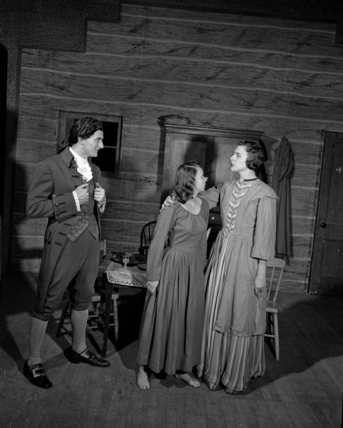 Two actresses and one actor in costume, portraying pre-Revolutionary New England characters in the drama, "The Devil's Disciple" by George Bernard Shaw. The actors are part of the Wisconsin Players, University of Wisconsin theatre group. Actresses are Beverly Mae Muth and Rosemary Arnock. Bruce Kanitz at right, is portraying Richard Dudgeon, who pledges his soul to the devil.