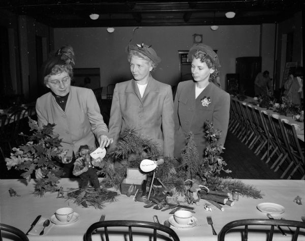 Members of the Sunset Garden Club decorate a table in the guild hall at Grace Episcopal Church for the kick-off luncheon for the Madison Community Chest drive. From left are: Mrs. Oscar (Tressie) Peterson, Mrs. R.O. (Helen) Wissler, and Mrs. Joseph (Maybelle) Otterson.