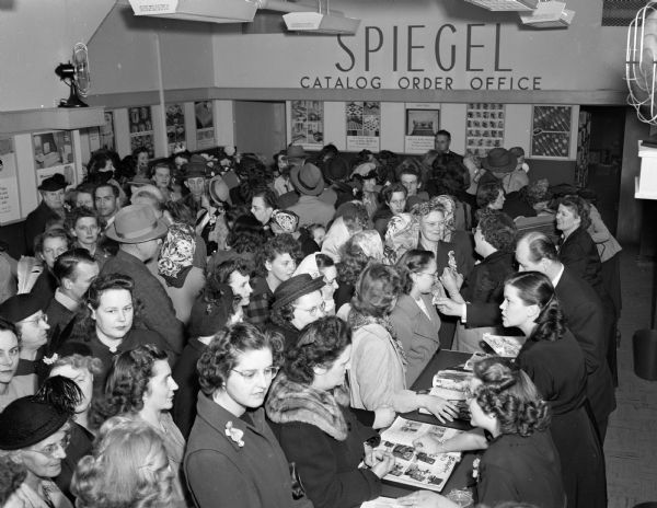 Interior of Spiegel Catalog Order Office, 427 State Street, with a crowd of shoppers.