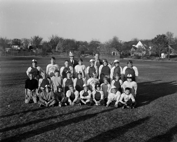 Group portrait of members of the Shorewood Hills grade school football team following their victory over the Lakewood grade school football team of Maple Bluff. Their coach and a village supporter are standing in the back row.