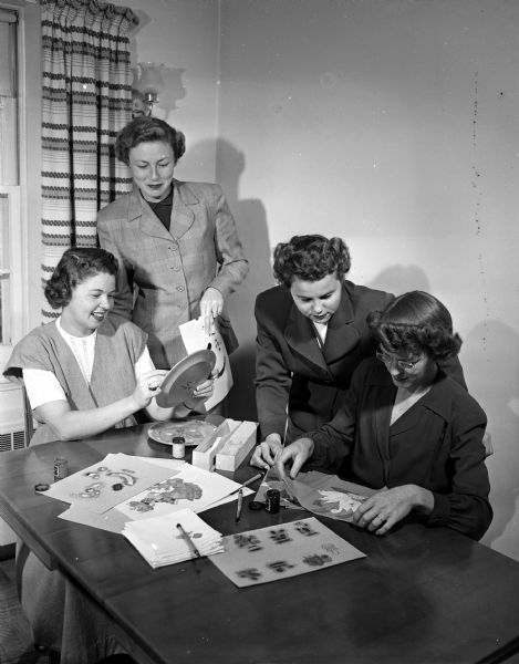 Four members of the handicraft group of the Junior division of the University League as they meet at the home of Mrs. David Soper to do some textile painting and stenciling. From left to right are: Mrs. George Davis; Mrs. H.W. (Jean) Engelman, vice-president of the Junior division; Mrs. Soper, chairman of the handicraft group; and Mrs. Burton H. Colvin. The Junior division includes new woman faculty members of the University of Wisconsin and the wives of new faculty members.