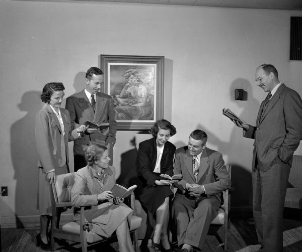 Three members of the play-reading group of the Junior Division of the University League and their husbands meet to read a play. Standing left to right are: Mrs. Eugene N. (Adrienne M.) Cameron, Mr. Cameron, and George P. Woollard. Seated from left to right are: Mrs. (Eleanore M.) Woollard, Mrs. Reid (Frances) Bryson, and Mr. Bryson. The Junior Division includes new women faculty members of the University of Wisconsin and the wives of new faculty members.