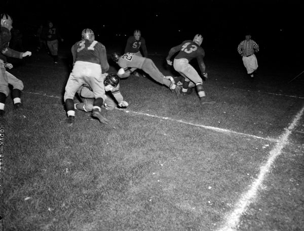 Madison Central High School fullback Willy Mischke (#22) carries the ball against Madison East High School in a football game at Breese Stevens Field. Also in the picture are Madison East High School players Ted Payn (49), Garky Messner (43), John Oasen (37), and Gekorge Otis (51).