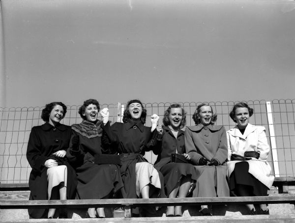 Pictured in the stands at Camp Randall Stadium are the wives of six members of the University of Wisconsin football team. From left to right are: Mrs. William Gable, Mrs. John Simcic, Mrs. Charles Halverson, Mrs. Robert Radcliffe, Mrs. Paul Kessenich, and Mrs. Kenneth Sachtjen.