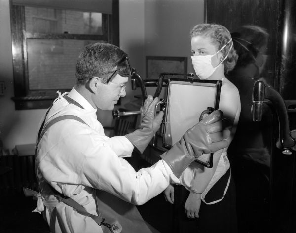 Doris Trameri, 568 Park Lane, re-enacts receiving a routine chest x-ray at the free chest clinic operated by the Madison Department of Public Health. Dr. James M. Wilkie is reading the x-ray.  Trameri was diagnosed with tuberculosis in June, 1947.