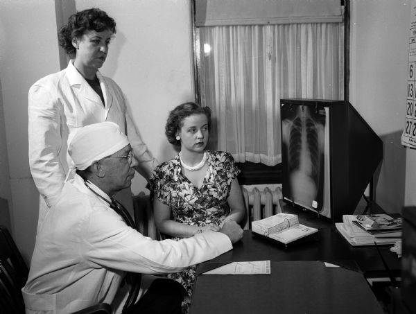 Doris Trameri, previously diagnosed with tuberculosis, reenacts being admitted to Lake View Sanatorium on July 9, 1947. Discussing her case are Dr. John K. Shumate, superintendent and medical director of Lake View and Alice Fox, director of social service in the out-patient department.