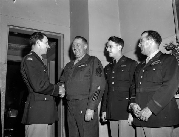 Special tribute was paid to Sgt. Leo H. Imhoff, second from the left, for his 20 years of service in the National Guard at the annual Military Ball which Company G, 128th Infantry, 32nd Division, of the Wisconsin National Guard, gave in the Blue Room of the Park Hotel. Sergeant Imhoff is shown being congratulated by Captain Arthur Kessenich, the battalion commander, left; and to the right of Sergeant Imhoff, Lieut. Herbert Phillips, commander of Company G., and Major Lawrence T. Burdick, of the adjutant general's office.