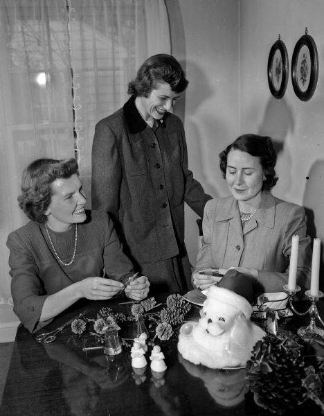 Mary Beach (left), social chairman; Mrs. George Kane, President; and Arabelle Murphy, chairman of the Christmas party making decorations for the annual formal Christmas dinner dance of the Naval Officers and Wives Club.