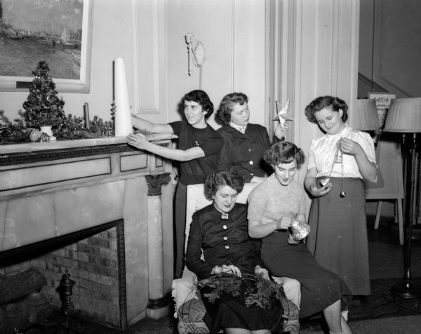 Five members of various YWCA organizations inspecting decorations to be used in the traditional "Hanging of the Greens" at the YWCA. Seated from left to right are: Jane Koch and Delores Day. Standing from left to right are: Marilyn Jenni, Lois Belt, and Bette Bleck.