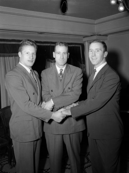 University of Wisconsin football coach Ivy Williamson (center) congratulates Badger stars Ken Huxhold (left) from Kenosha, 1950 team captain, and All-American Bob Wilson (right), chosen by his teammates as "most valuable" at the annual football banquet.