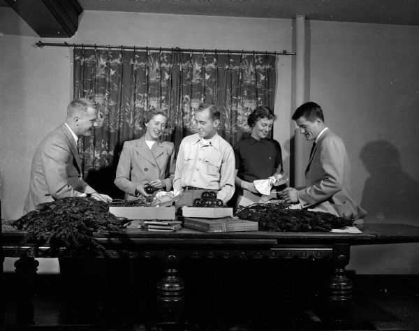 Two women and three men look over Christmas decorations in preparation for the annual Christmas Subscription Dance, an event for university students and young marrieds. From left to right are: Bill Piper, Elizabeth Johnson, David Davies, Mary Young, and Richard Johnson.