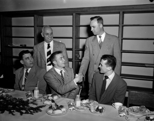 Seated at the head table of the West High School football banquet are, (left to right): Bob Odell, University of Wisconsin backfield coach and main speaker; Evert Wallenfeldt, team captain; and Dave Matson, a senior guard and the toastmaster. Standing, left to right, are: Willis Jones, West High coach; and principal Ralph Christoffersen.