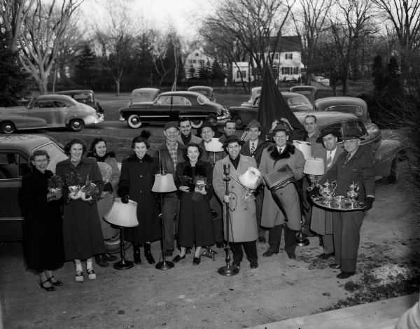 Sixteen employees of the Rennebohm Drug Company carry miscellaneous furnishings from the old executive residence to the new one in Maple Bluff. The "moving session" was a surprise Christmas gift for the "boss" and his wife.