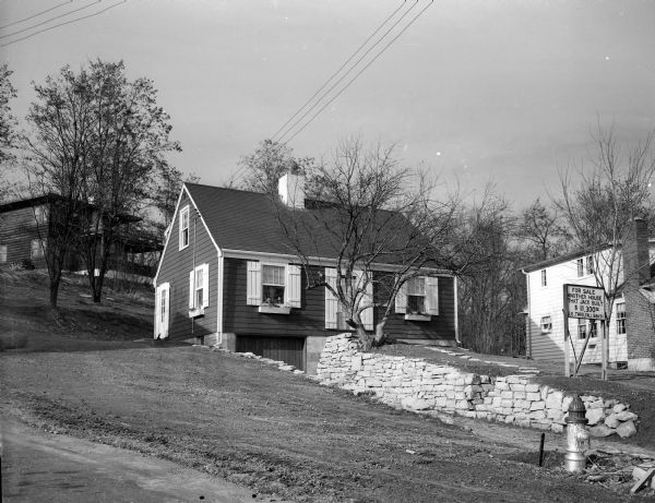 View of a house in the Crestwood neighborhood built by Jack Threlfall in a Madison shop and assembled on site. A sign in the front yard reads: "For Sale Another House That Jack Built $11,300.00 J.B. Threlfall 58671".