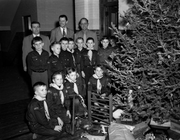Cub Scouts of Pack 333 gather around the Christmas tree at Lowell School for their annual Christmas party. Standing in ther back row, left to right, are: James Fosnot, assistant cubmaster; Don Efinger, cubmaster; and Lars M. Hanson, pack committee secretary-treasurer.