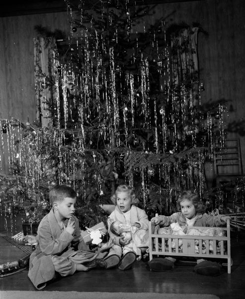 Tommy, age 7, Kathy, age 3, and Peggy, age 2, children of Willard S. and Mary Ellen Stafford, sitting at the base of their Christmas tree at their residence, 5725 Middleton Road.