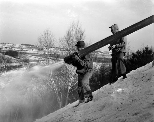 Two members of the Blackhawk Ski Club spray the landing hill at the club's ski jump at Tomahawk Ridge west of Middleton.