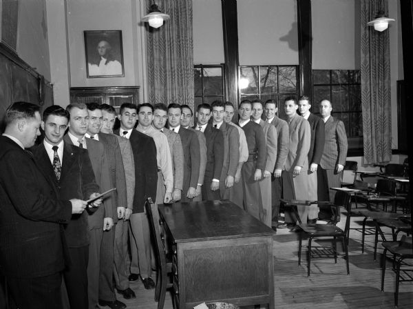 Seventeen police rookies and graduates of the Madison Police Department stand in a line at their very first pre-service training course. They began their new duties the night of their graduation, Dec. 31, 1949.