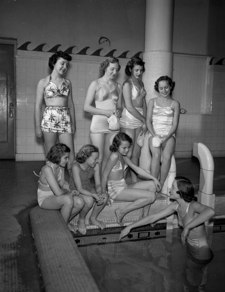 Instructor Doris Greene, at right, teaches swimming class to seven young women as part of the YWCA Winter Activities program. At the edge of the pool are (left to right), front row: Carol Hauser, 309 South Midvale Boulevard.; Sally Crownhart, 2115 Bascom Street; and Salllyl Stephan, 428 Castle Place. Back row: Donna Trainor, 133 South Franklin Street; Lucille Hummermeir, 2018 East Washington Avenue; P. Allen, 4025 Hiawatha Drive; and Roberta Caldwell, 4134 Cherokee Drive.