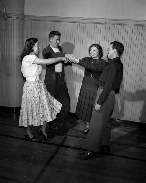 Two couples square dance as part of the YWCA Winter Activities program.  Dancers are left to right: Julia Way, 209 Corry Street; Paul Laube, Durand, Illinois; Lois Belt, 312 North Carroll Street; and Gordon Shelhamer of Sun Prairie.