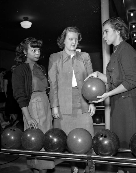 Jo Ann Walker, bowling instructor, demonstrates bowling technique to Catherine Greene and Elsa Tamminga at the Plaza Alleys as part of the YWCA winter activities program.