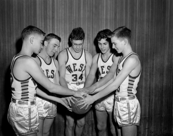 Uniformed members of the West High School basketball team gather with their hands on a ball.  They are, from left to right, are: Jerry Quinn, Jim Clapp, Jack Mansfield, Bill Marshall, Tom Mack.