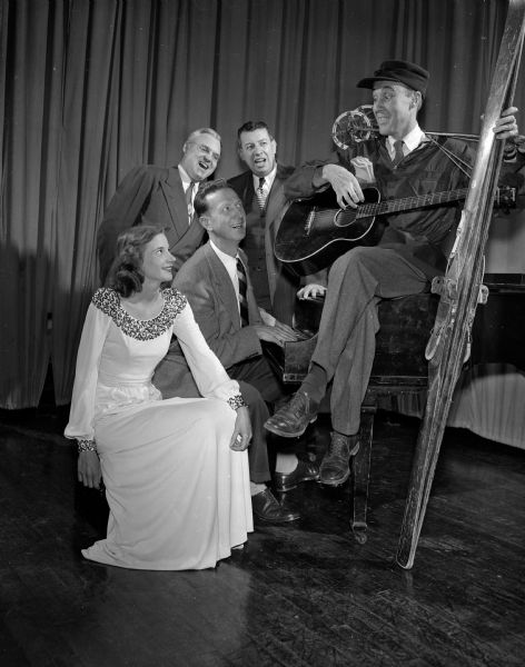 View of a Home Talent Comedy performance by Charles C. Bradley, imitating Helen Morgan and singing to Mae Zimmerman of 311 North Frances Street. The background trio is Whitford Huff, 1017 Tumalo Trail, at the piano, (right) Cyril M. Howard, 4154 Nakoma Road, (center), Harold F. Brandenburg, 4104 Hiawatha Drive.