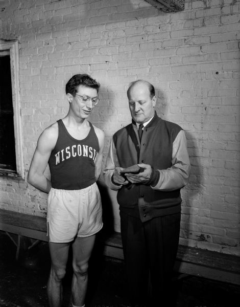 U.W. Madison track coach Guy Sundt, right, examining new track shoes with his star miler, Don Gehrmann, who once ran a mile race in 4:09.5 minutes.