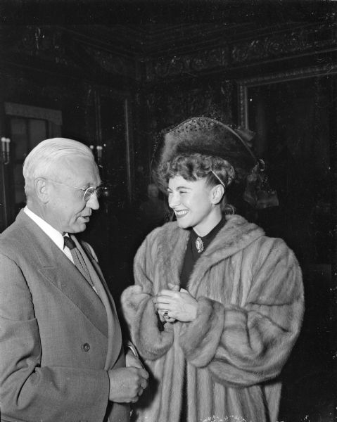 Entertainer and pianist Hildegarde, born Hildegarde Loretta Sell, is shown in fur coat with Governor Oscar Rennebohm. She is a Wisconsin native born in Adell, Wisconsin. She was in Madison for a performance at the Capitol Theatre. Two of her cousins live in Madison, Truman Graf and Mrs. Benjamin Bierer.