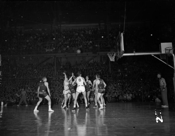 Action photograph of the Wisconsin-Minnesota basketball game at the U.W. Madison Fieldhouse. Wisconsin players are Marshall "Danny" Markham (left) and Ab Nicholls (8). Minnesota players are Jerry Mitchell (35), Whitey Skoog (41), and Maynard Johnson (1).